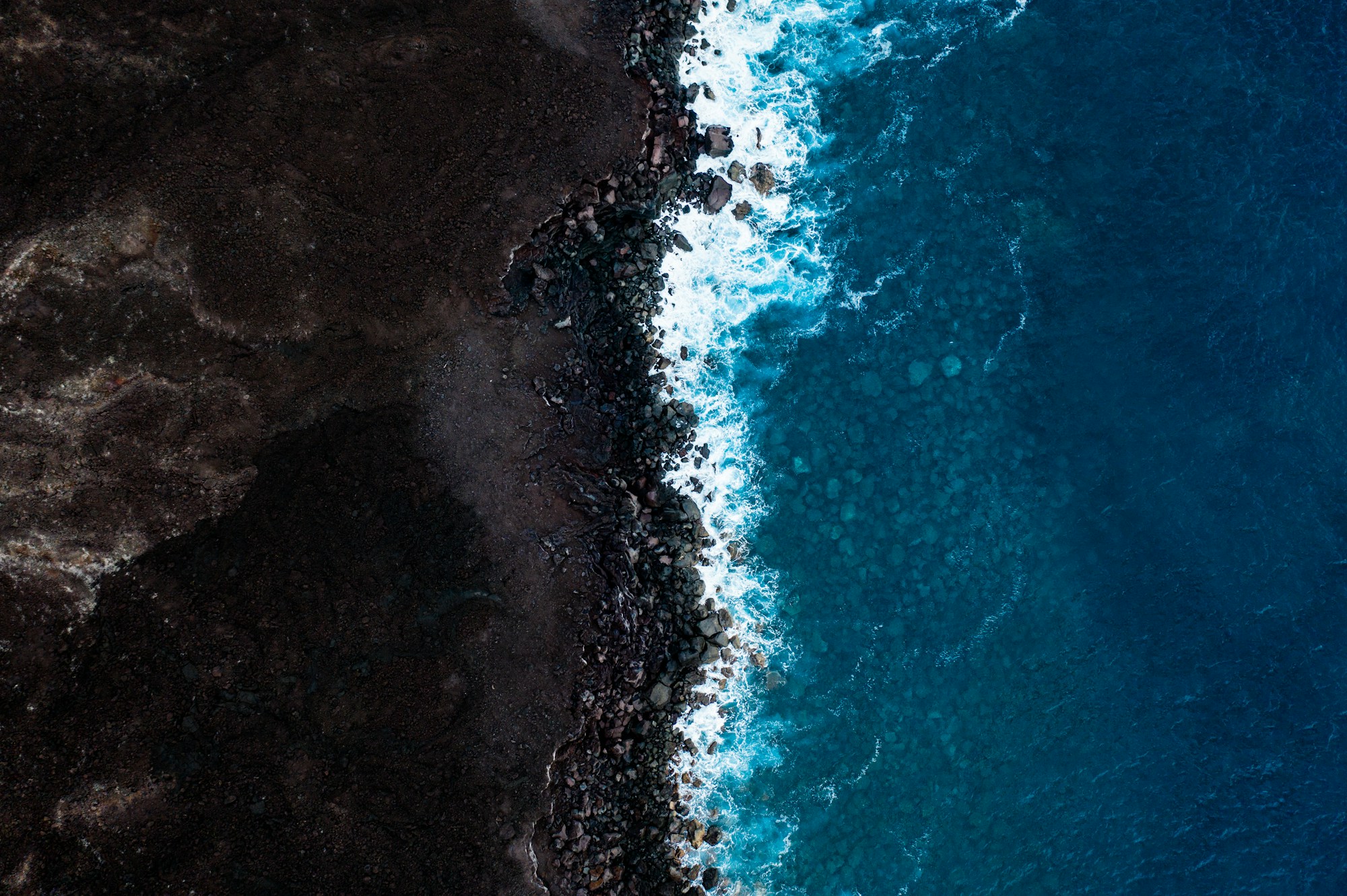 Ocean waves meeting a dramatic dark coastline